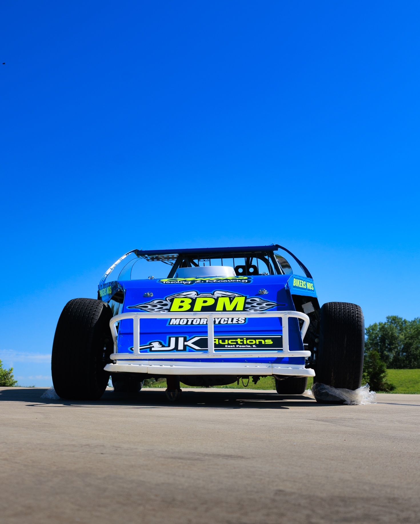 Blue and white race truck with BPM branding on a road under a clear blue sky