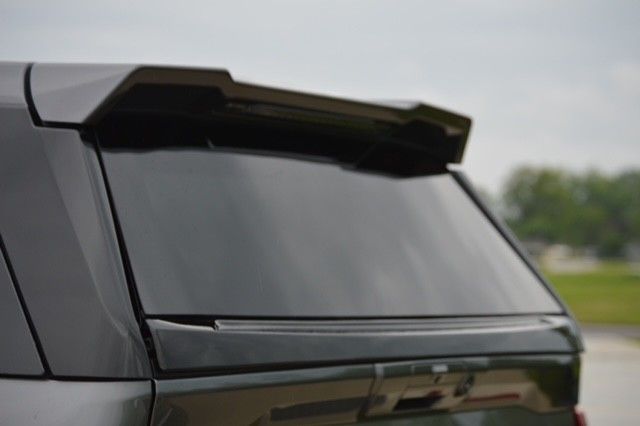 Rear view of a black SUV with a roof spoiler and tinted rear window outdoors