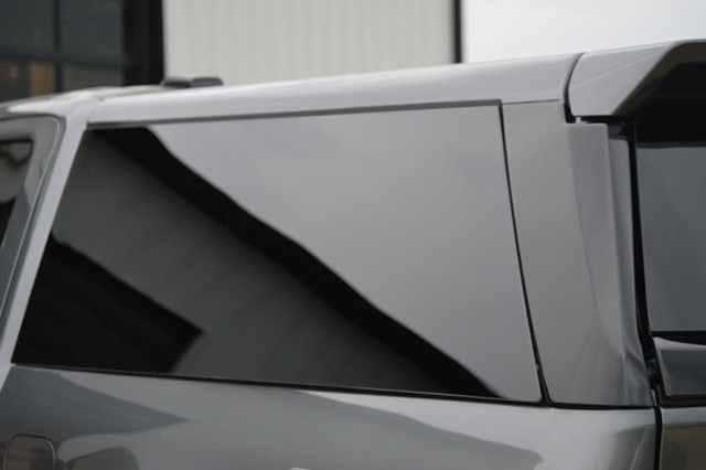 Close-up of a gray SUV’s tinted rear side window and door panel.