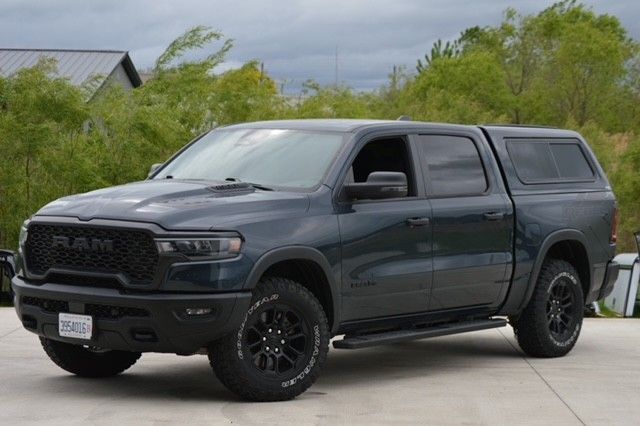 Dark gray pickup truck with canopy parked on a driveway under cloudy skies