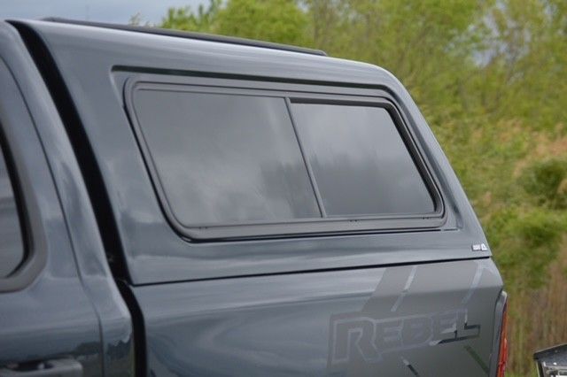 Close-up of a gray pickup truck canopy window with tinted glass and black trim