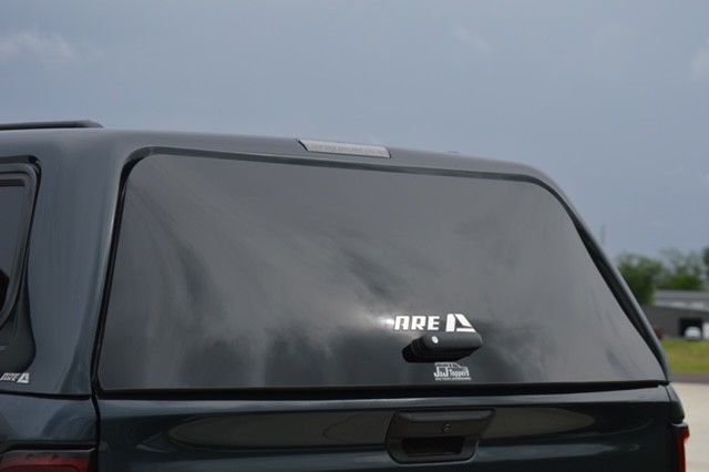 Rear view of a dark SUV with a rear window sticker on a cloudy day