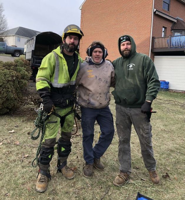 Three workers in work clothes standing together outdoors near a brick building