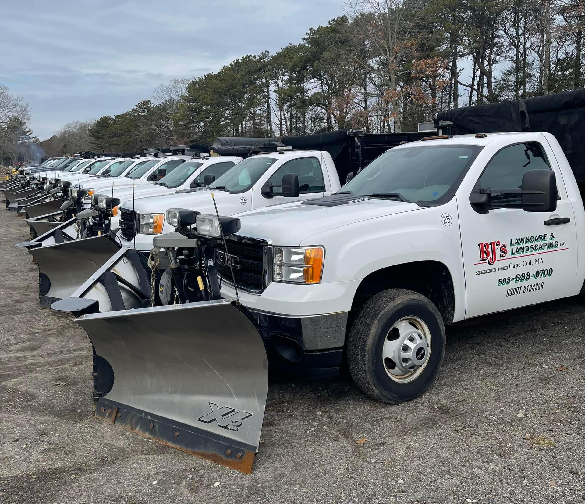 White pickup trucks with snowplows lined up in a row.