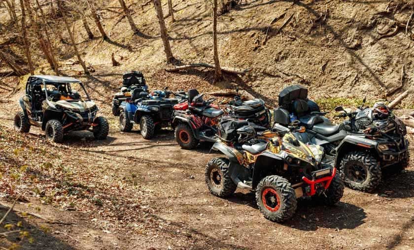 Group of ATVs parked on a dirt trail in a wooded area.