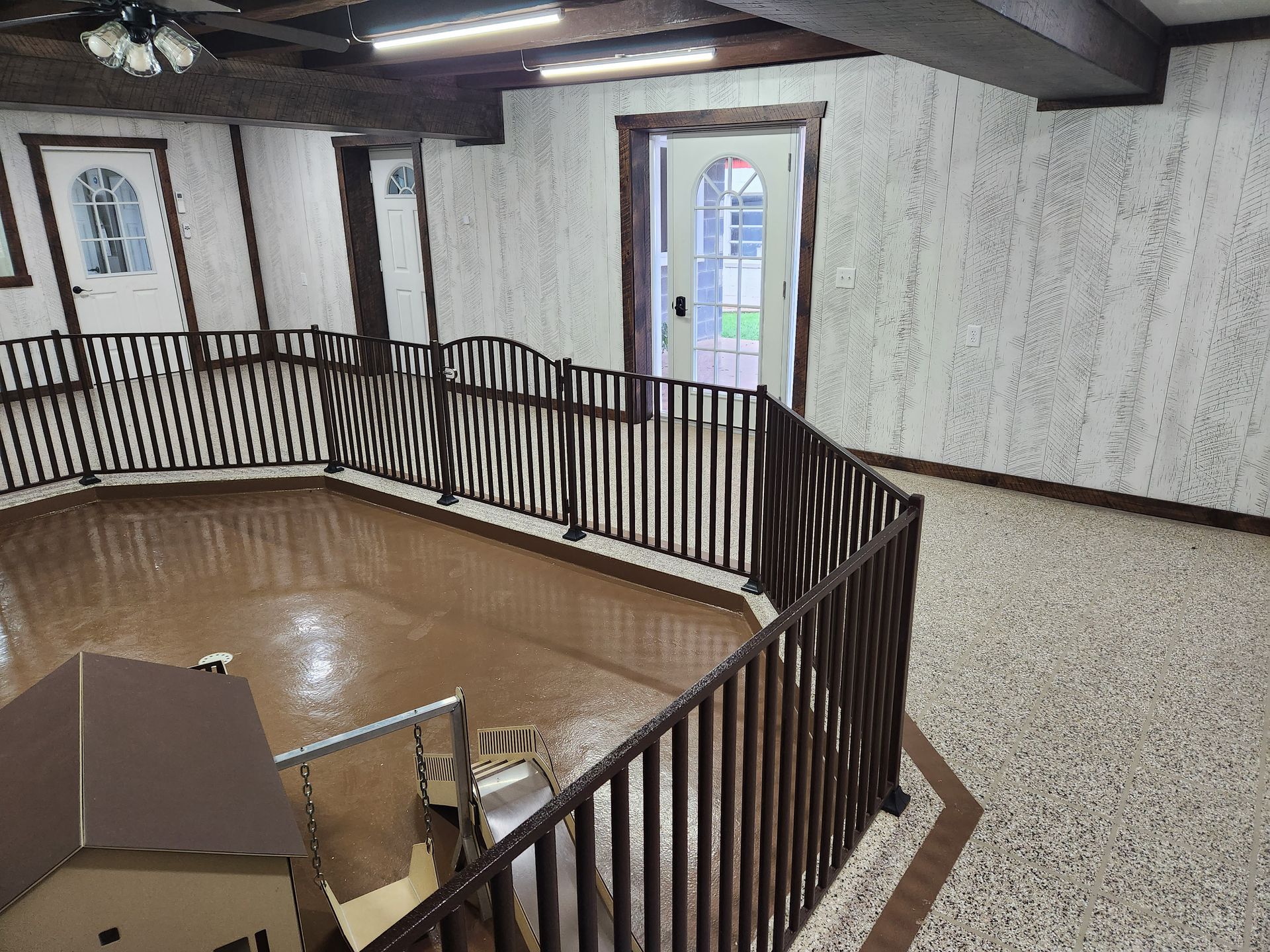 A room with a fence around it and a small house in the middle.