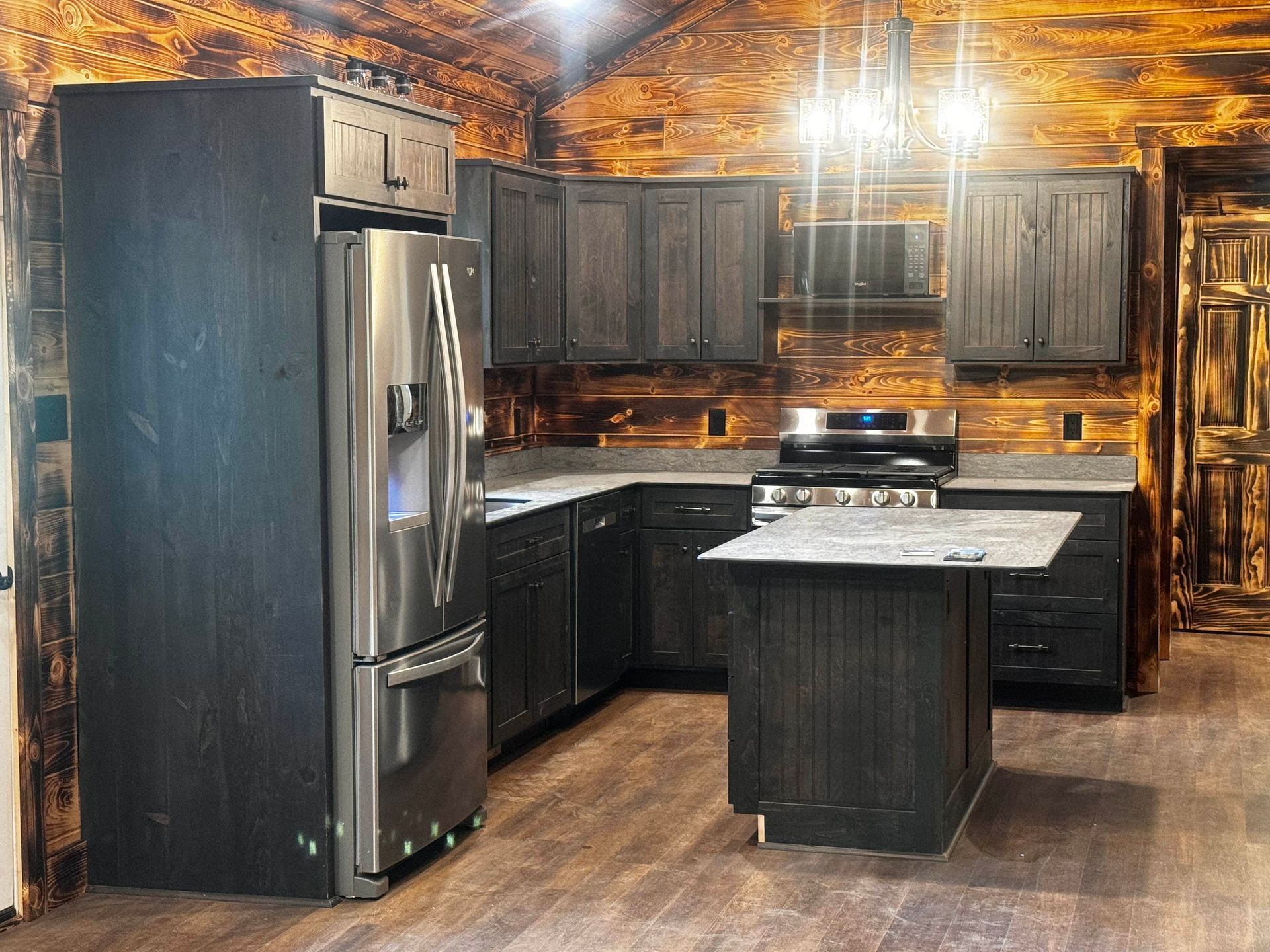 A kitchen in a log cabin with stainless steel appliances and black cabinets.