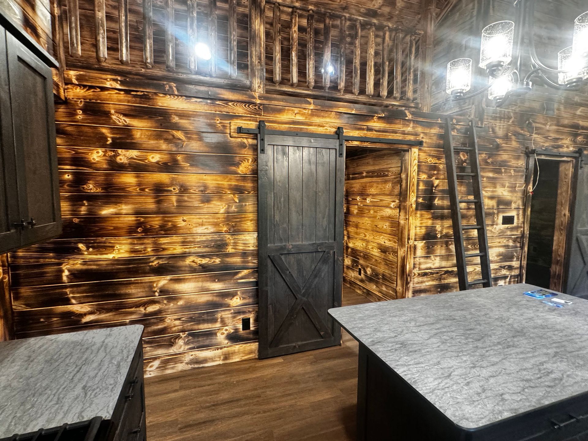 A kitchen with a sliding barn door and a ladder.