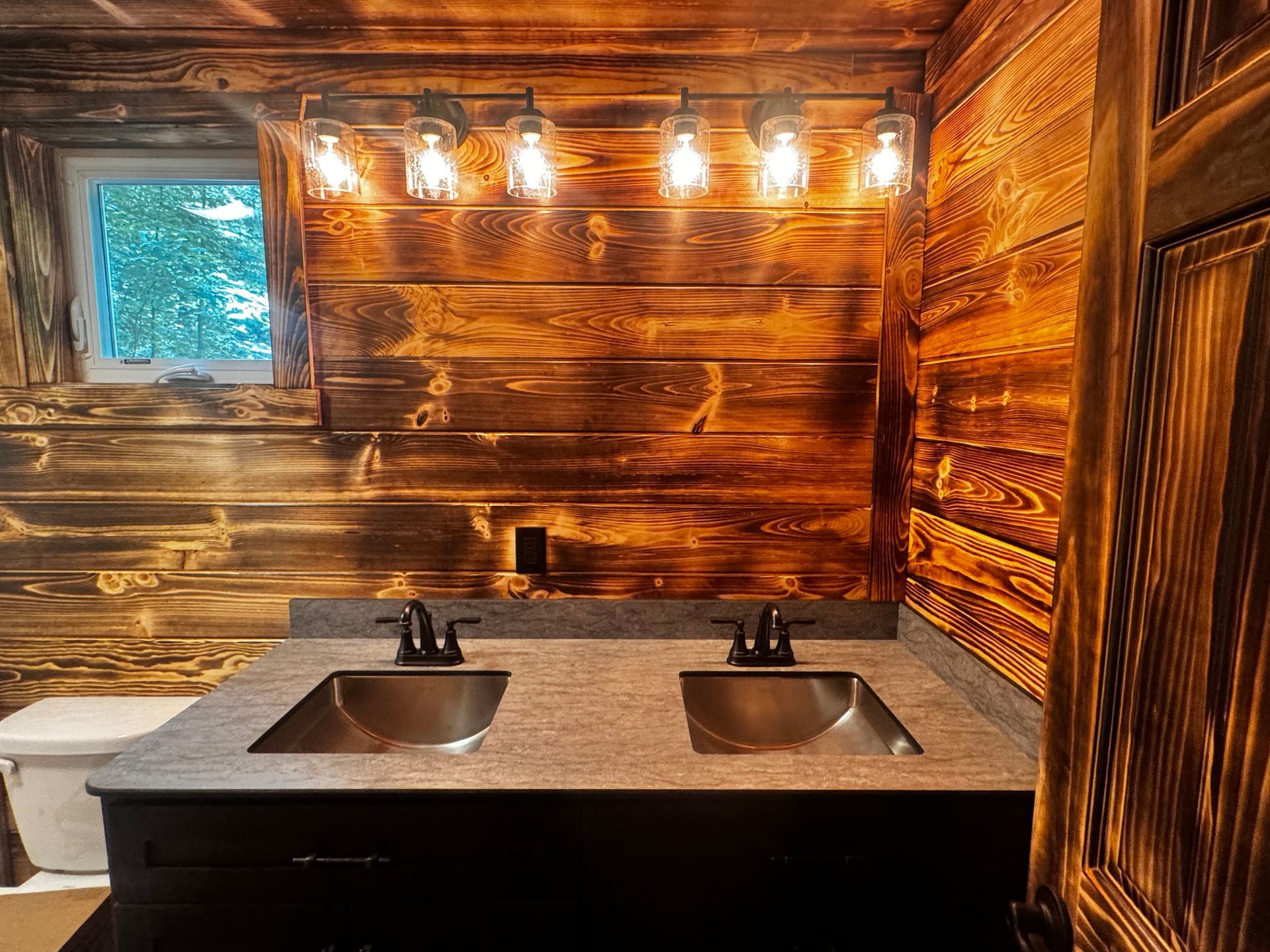 A bathroom with two sinks and a wooden wall.