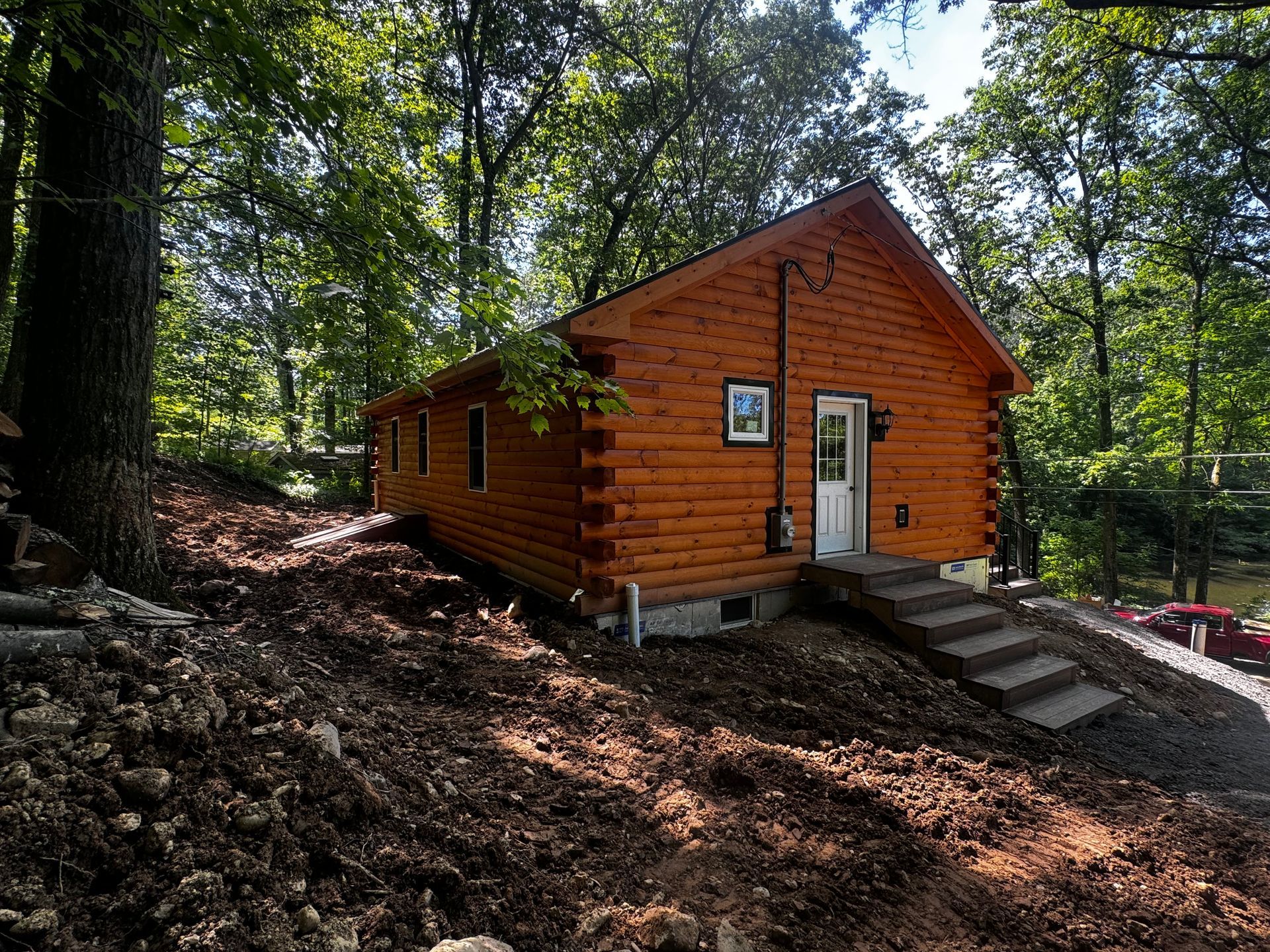 A log cabin is sitting on top of a hill in the middle of a forest.