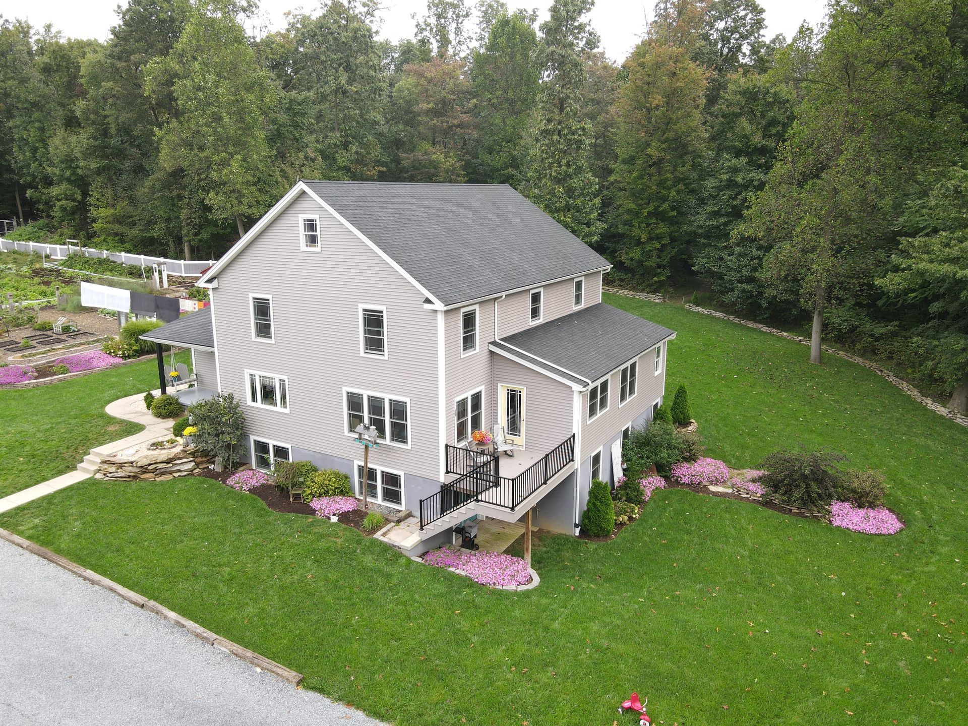 An aerial view of a large house with a lush green lawn surrounded by trees.