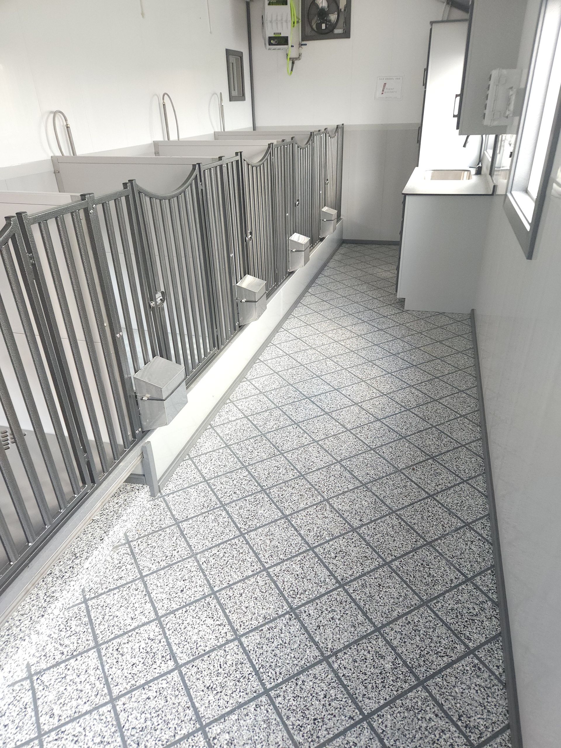 A black and white photo of a room with a tiled floor and a fence.