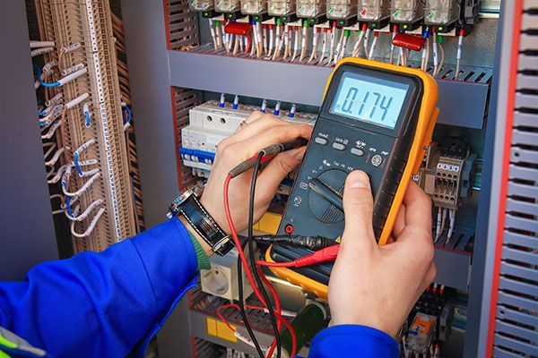 Electrician testing electrical panel with a multimeter.