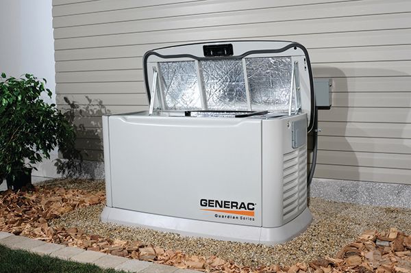 A Generac home generator is outdoors next to a house, lid open.