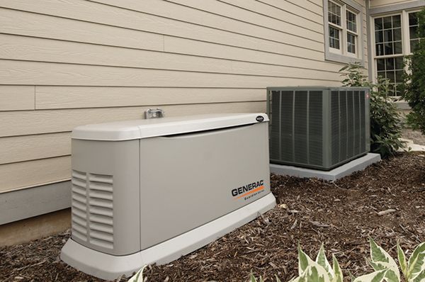 A tan Generac home generator next to an air conditioning unit against a beige house.