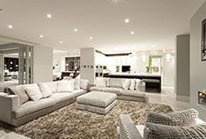 Spacious living room with neutral colors, couches, fluffy rug, and recessed lighting.