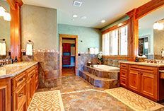 Bathroom with wooden cabinetry, brown tile, and a bathtub on a raised platform.