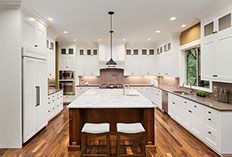 White kitchen with a wood island, stools, and wood flooring.