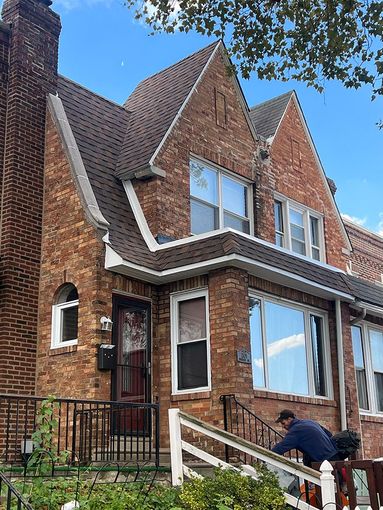 A man is working on the stairs of a brick house.