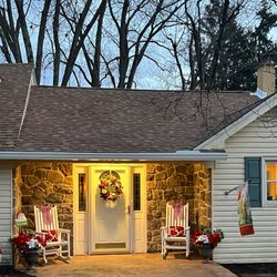 The front of the house is decorated for Christmas with rocking chairs and a wreath on the door.