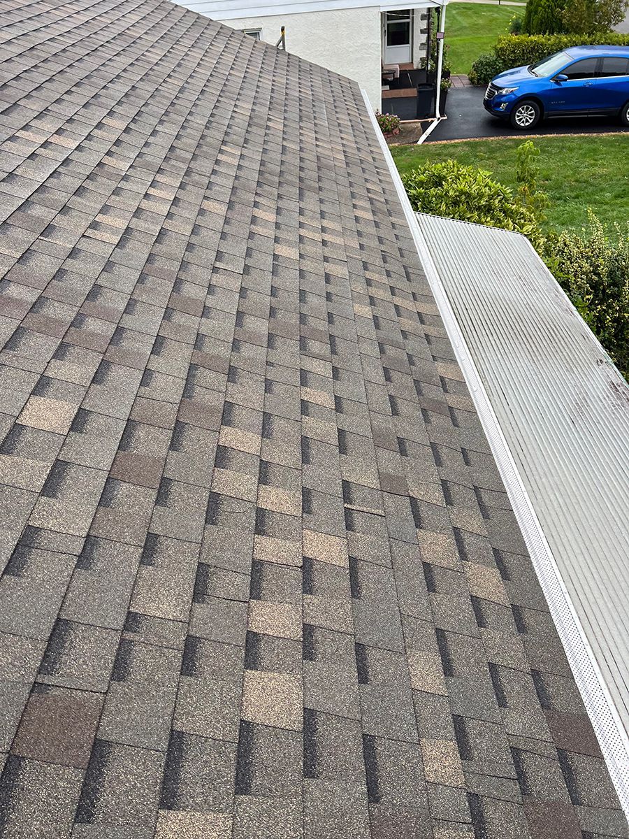 The roof of a house with a blue car parked in the driveway.