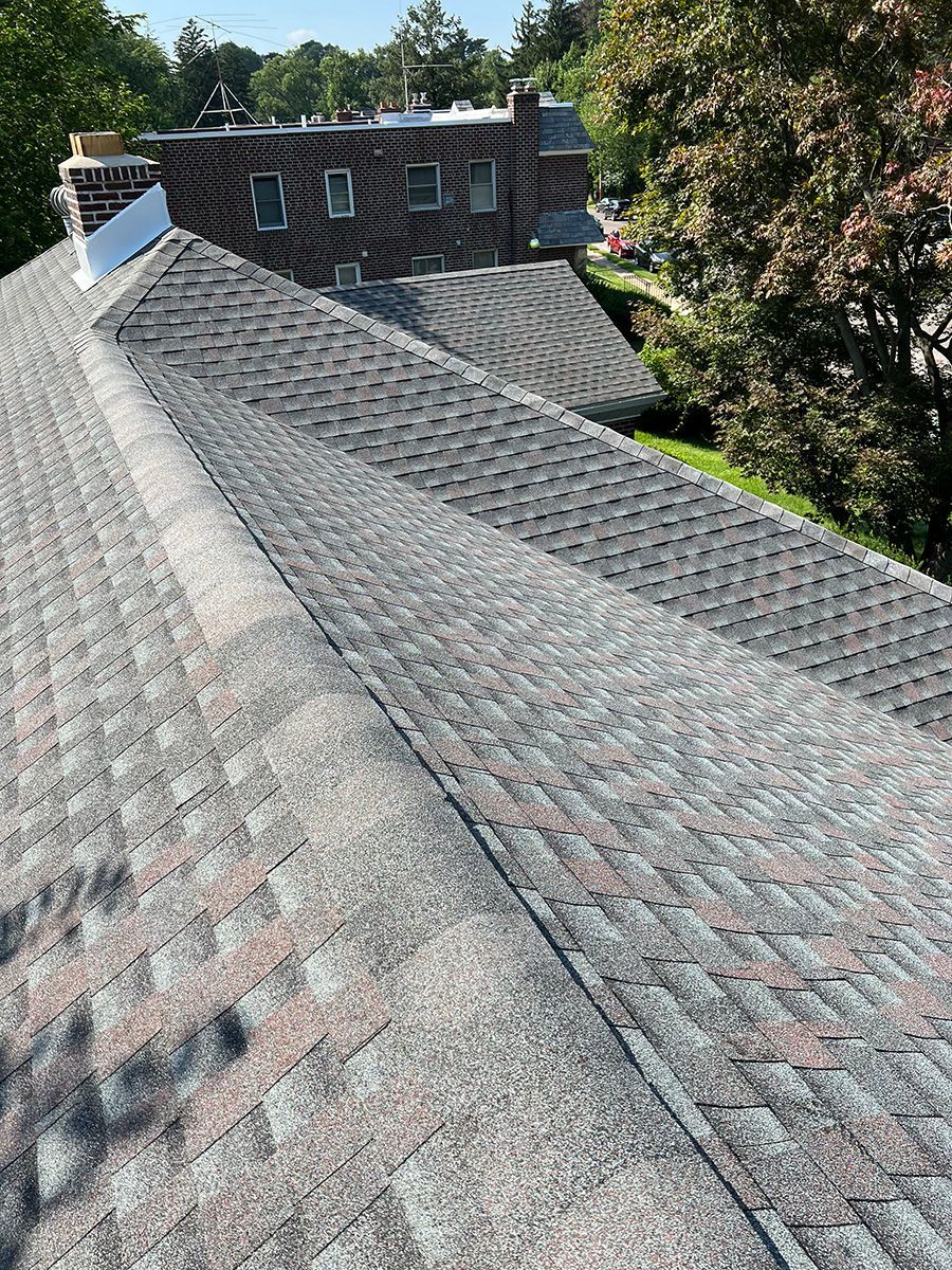 A close up of a roof with a brick building in the background.