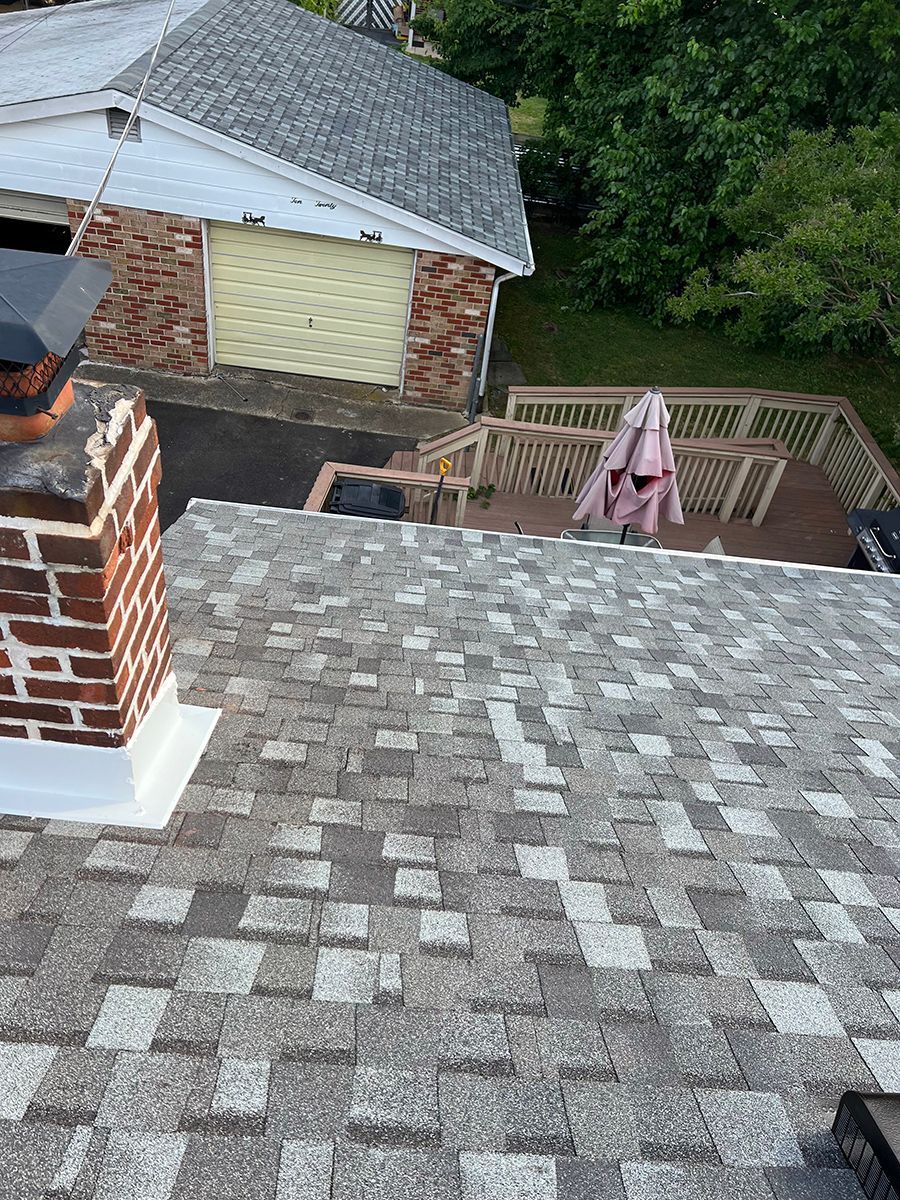 A roof with a chimney on it and a deck in the background.