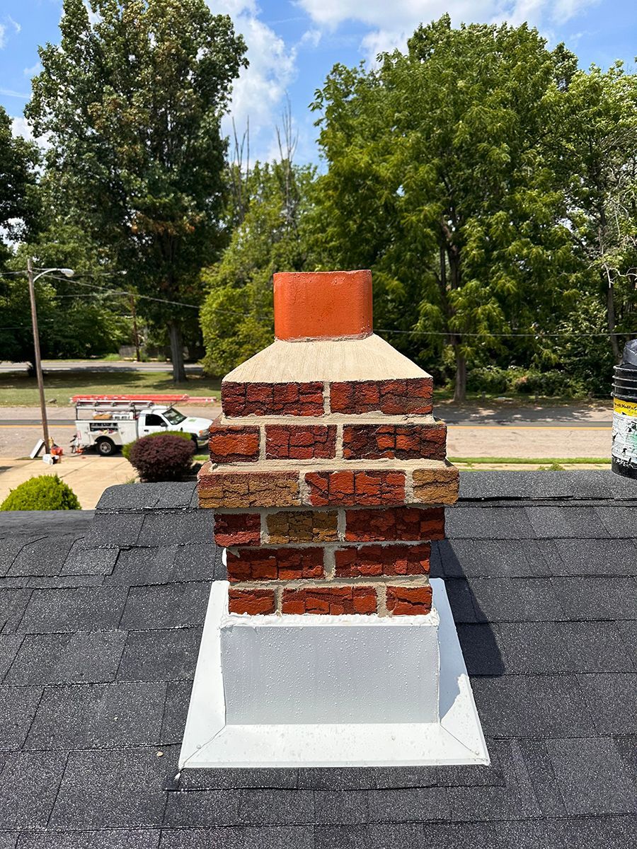 A brick chimney is sitting on top of a roof.