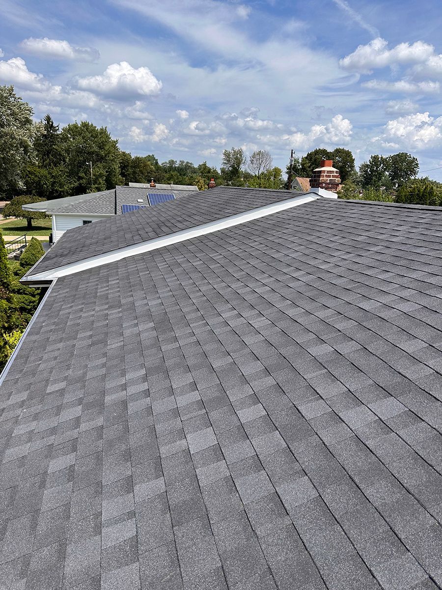 The roof of a house with a gray shingle roof and a chimney.