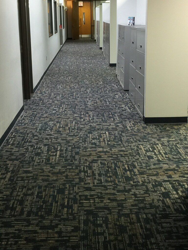 A long hallway with a carpeted floor in an office building.