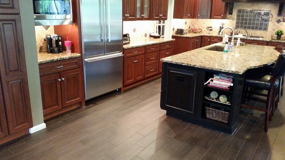 A kitchen with wooden cabinets , granite counter tops , stainless steel appliances and a large island.