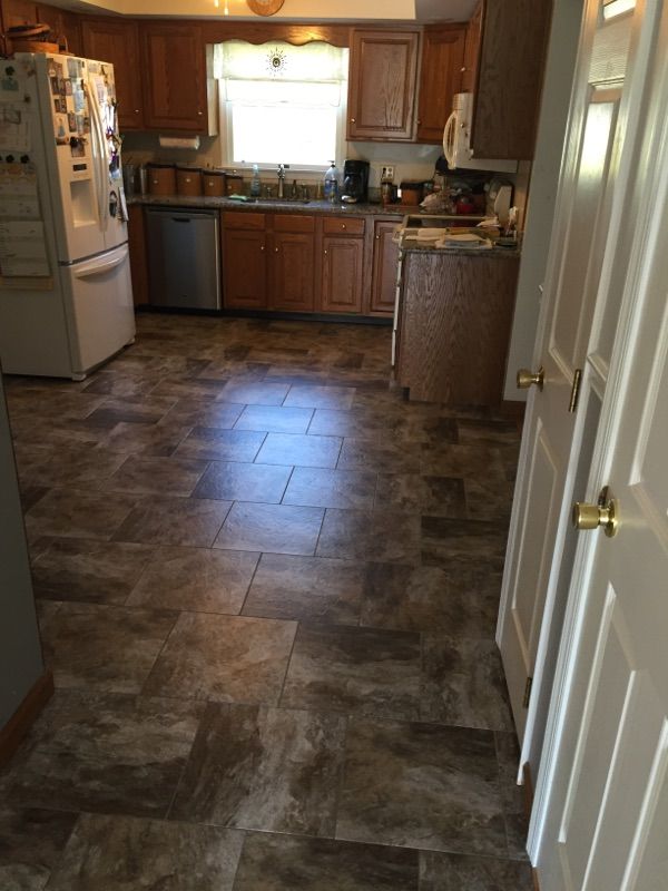 A kitchen with a tile floor and wooden cabinets