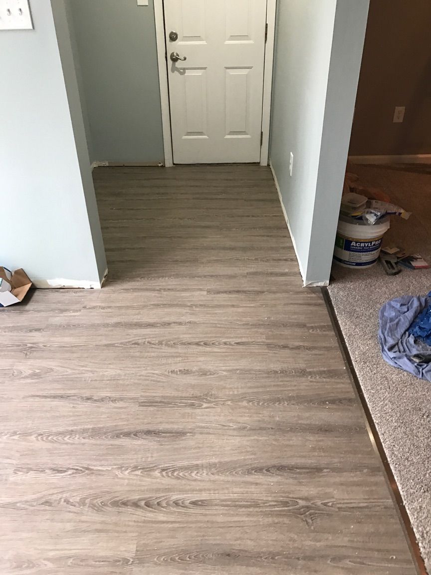A hallway with a wooden floor and a white door.
