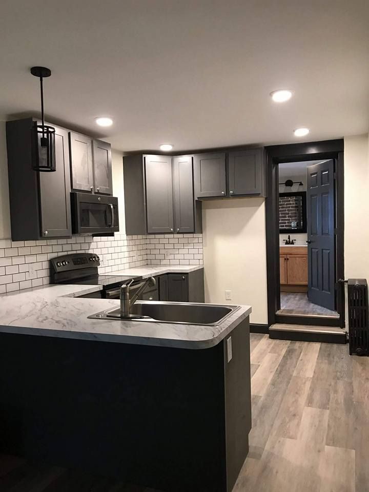 A kitchen with a sink , stove , microwave and cabinets.