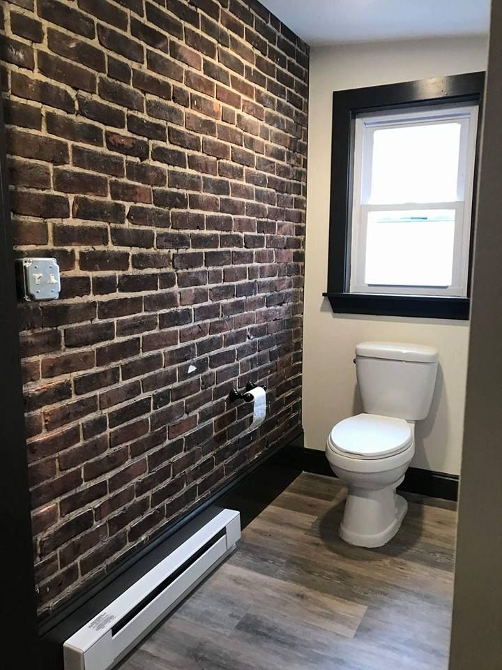 A bathroom with a brick wall and a toilet.