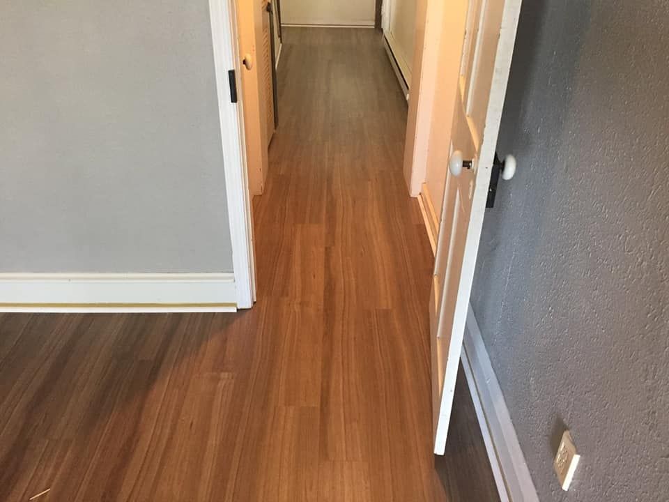 A long hallway with hardwood floors and white doors.