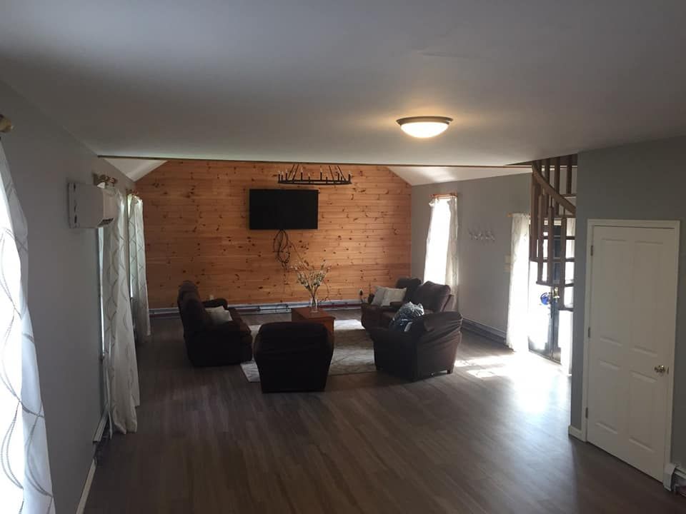 A living room with a couch , chairs and a flat screen tv.
