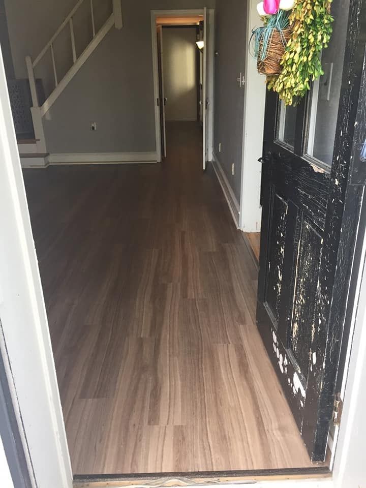 A hallway with hardwood floors and a black door in a house.