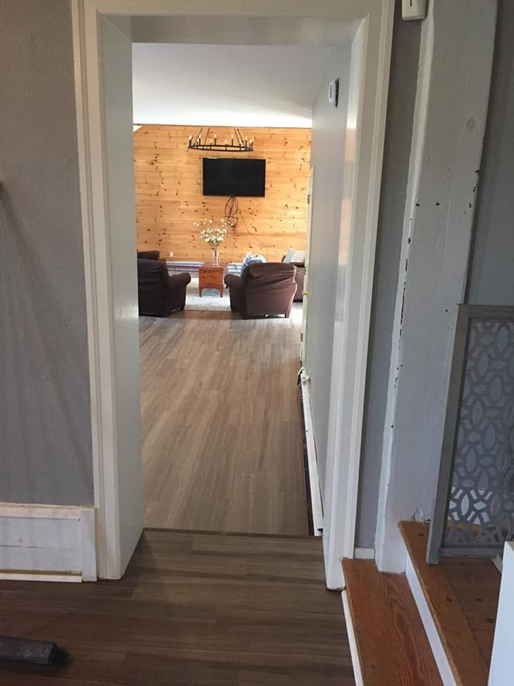 A doorway leading to a living room with a flat screen tv on the wall.