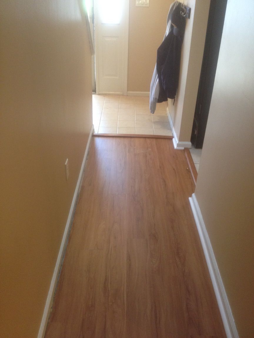 A hallway with hardwood floors and a coat hanging on the wall.