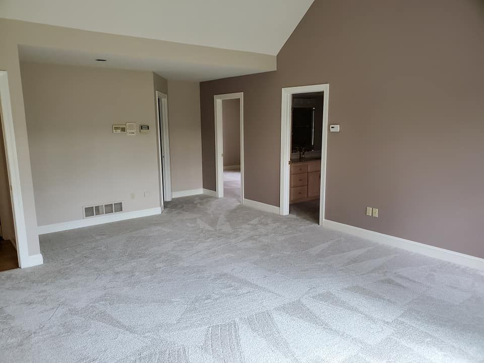 An empty room with a vaulted ceiling and a gray carpet