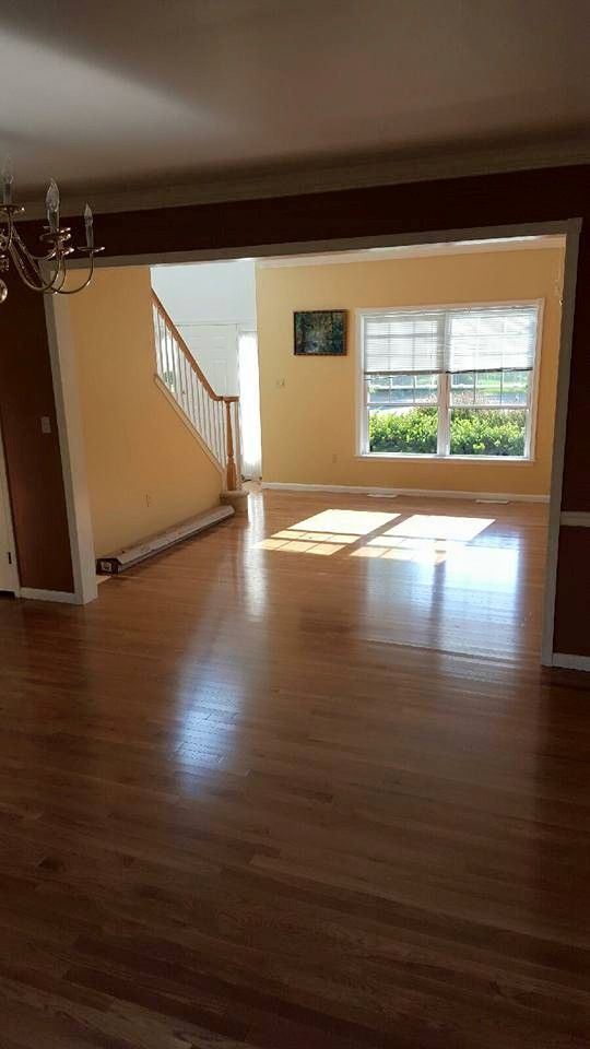 An empty living room with hardwood floors and a staircase.