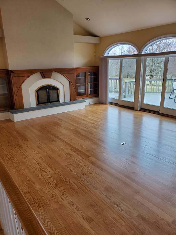 An empty living room with hardwood floors and a fireplace.