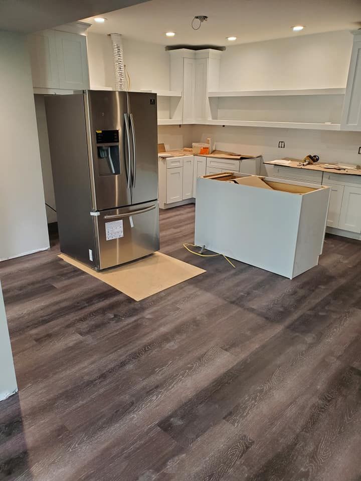 A kitchen with a stainless steel refrigerator and a wooden floor.