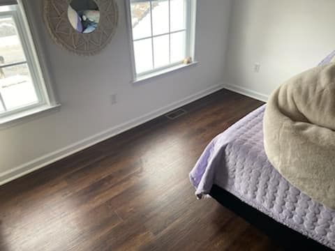 A bedroom with hardwood floors , a bed and a window.