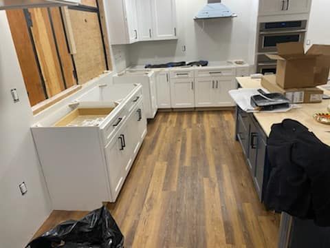 A kitchen with white cabinets and wooden floors is being remodeled.