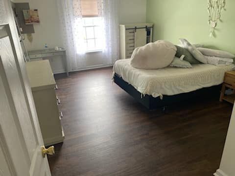 A bedroom with a bed , dresser , nightstand and window.