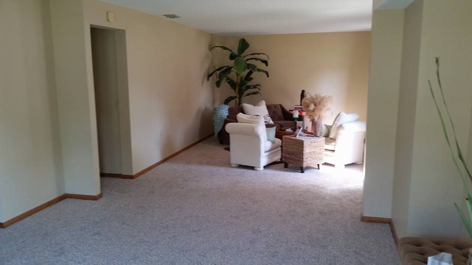 A living room with a couch , chairs , a table and a plant.