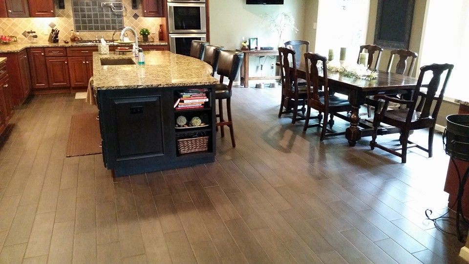 A kitchen with a large island , dining table and chairs.