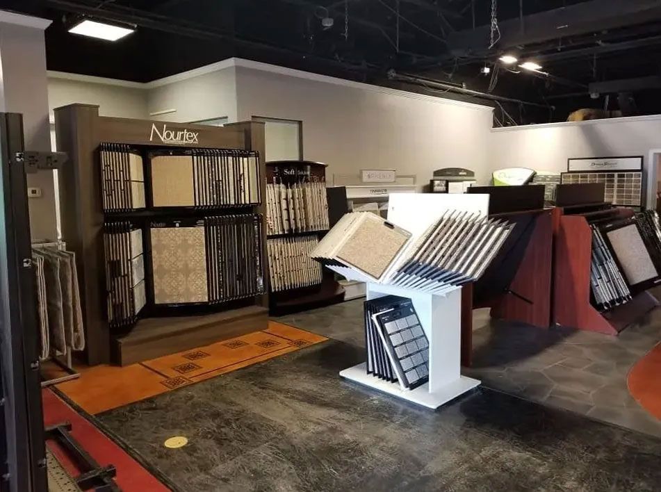 Carpet showroom with racks of rugs and sample displays on a gray floor